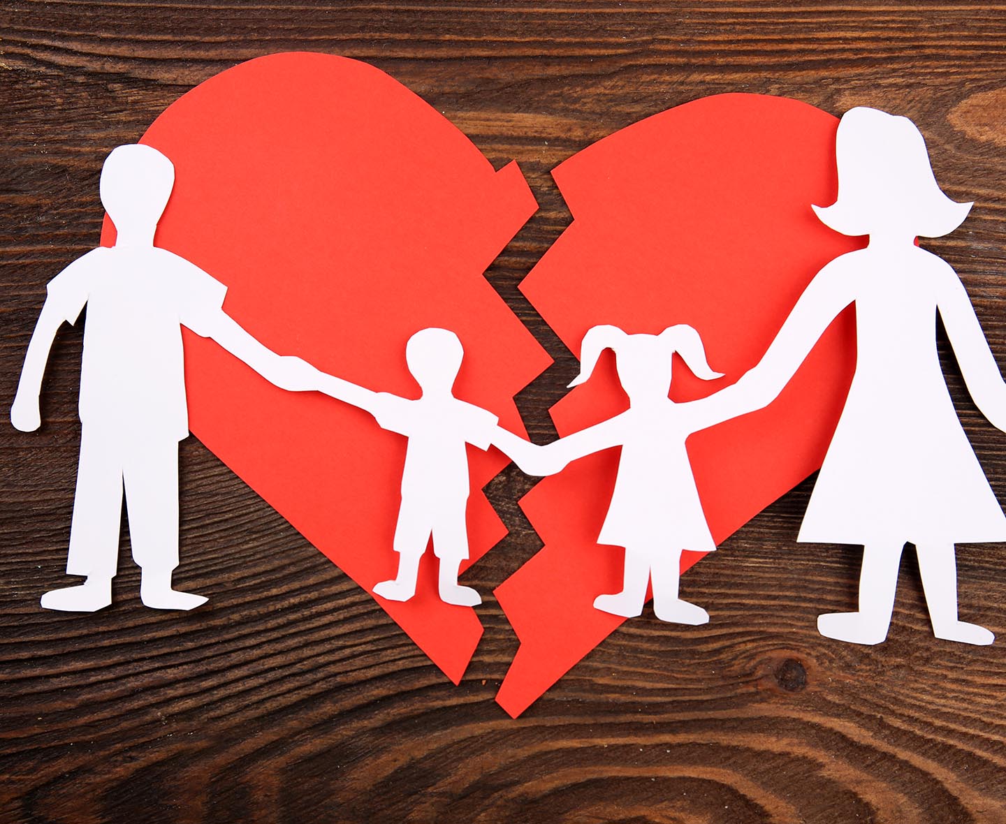 Paper cutout silhouette of a family split apart on a paper heart, divorce concept